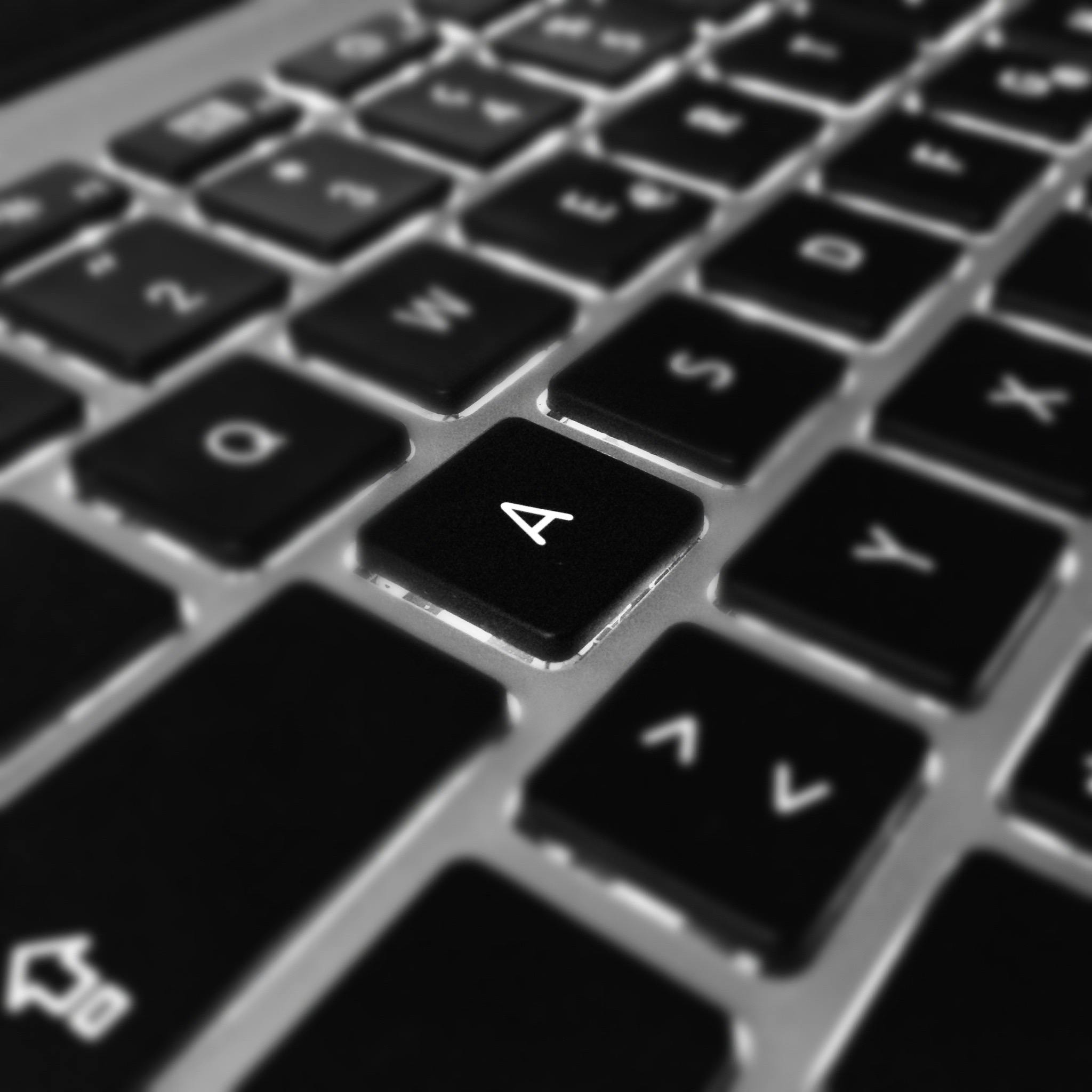 Artistic black and white close-up of a laptop keyboard focusing on the letter 'A'.
